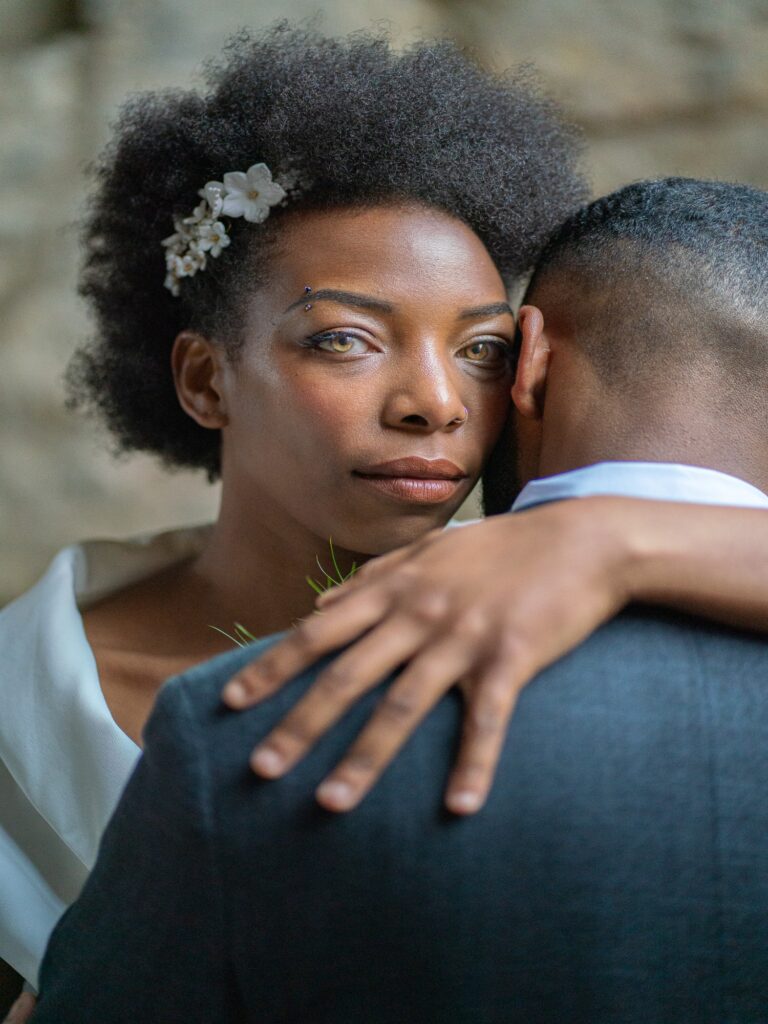 Bride looking straight at the camera over her groom’s shoulder