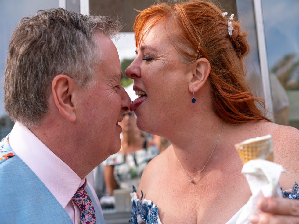 A hilarious and playful close-up portrait of the bride licking ice cream off the groom's nose. Authentic, fun-loving wedding photography by an easy-going wedding photographer.