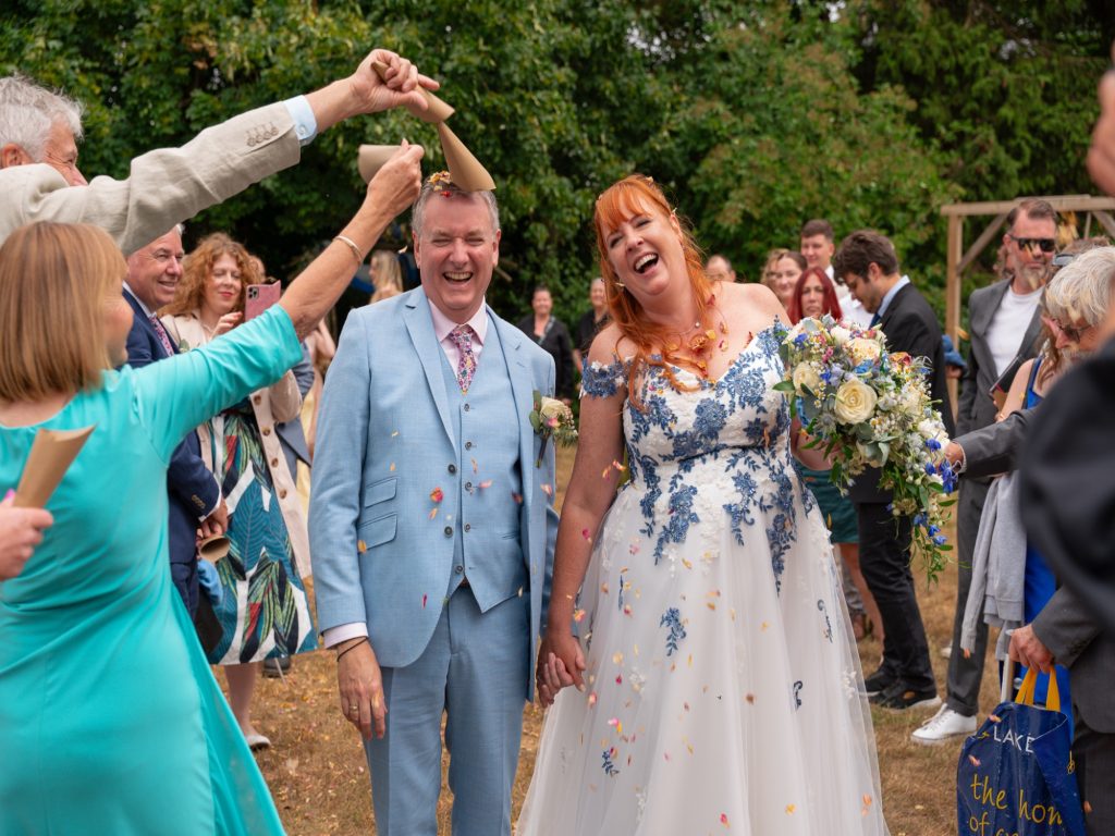 Bride and groom laughing as guests throw confetti at the Sadie Centre