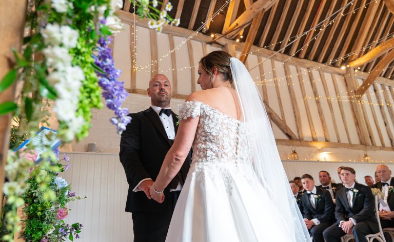 Bride and groom holding hands at the altar at The Barns at Alswick
