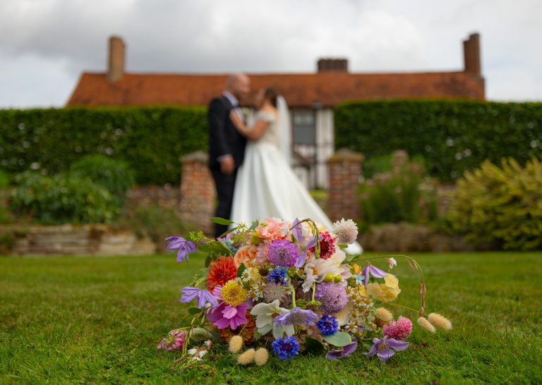Couple with a wildflower bouquet in the gardens at The Barns at Alswick