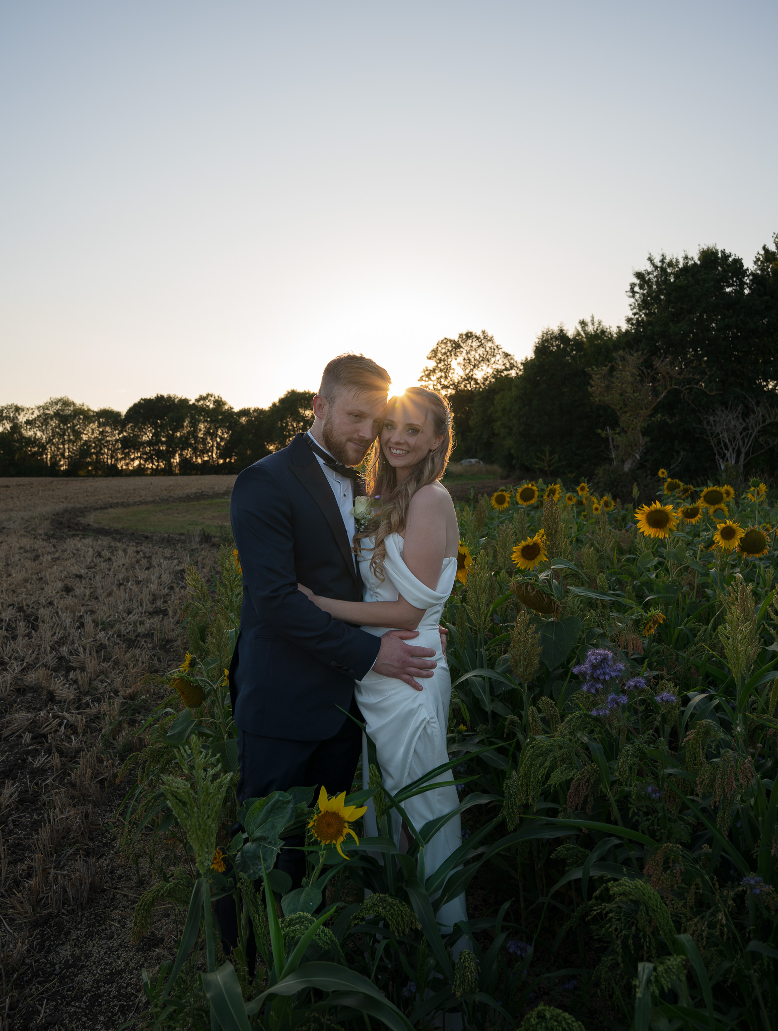 Molly and Tommy walk hand in hand through a pathway of guests blowing bubbles at The White Horse Southill, celebrating their wedding day.