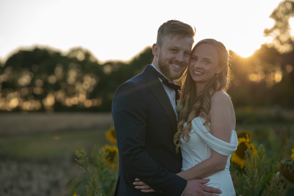 Bride and groom in sunflower field at sunset during Southill wedding at The White Horse, captured by Hertfordshire photographer TME Photography Herts.