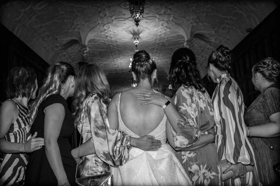 Bride and her close friends in a supportive embrace, captured from behind to showcase the intimacy and unity of the bridal party. Candid photography by a Hertfordshire wedding photographer.