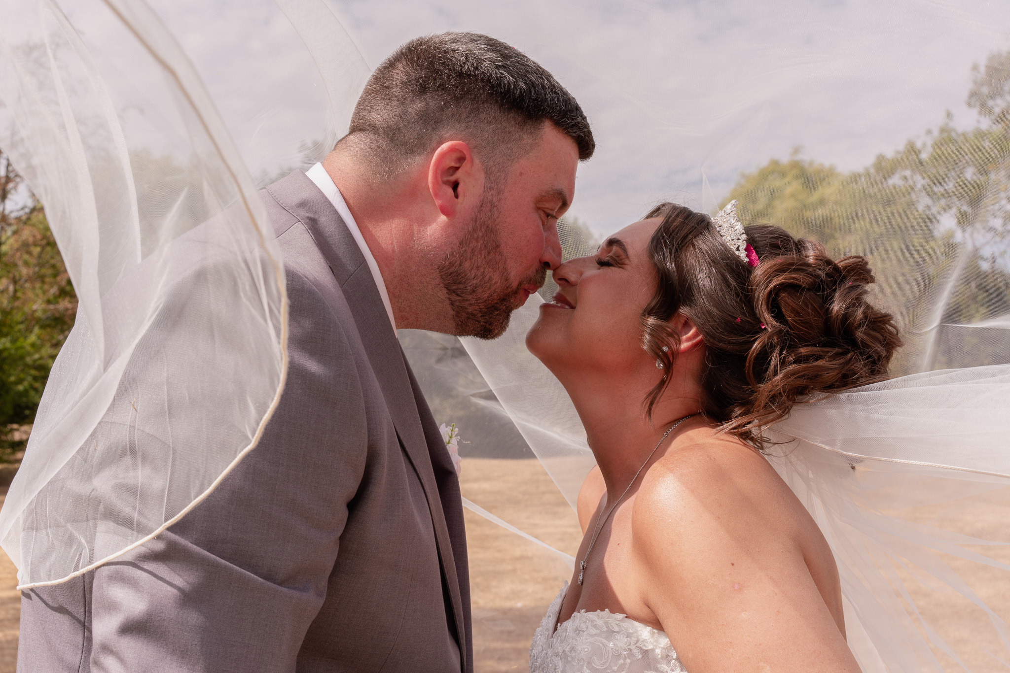 Black and white portrait of bride and groom about to kiss under veil, romantic wedding photography