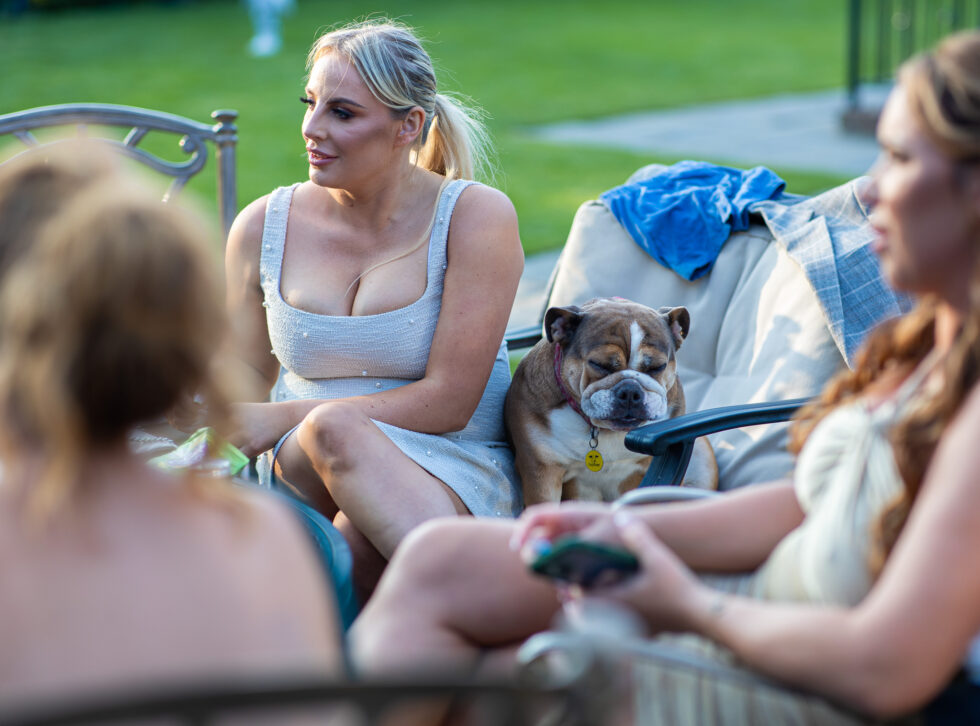 Wedding guests relaxing on the lawn with a small dog in the foreground
