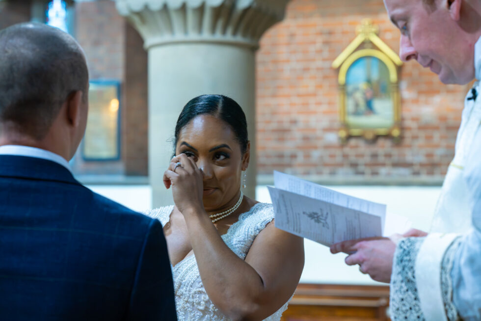 Emotional guest wiping away tears while reading an order of service in church