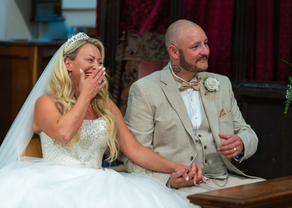 Bride and groom laughing and covering their faces during their ceremony