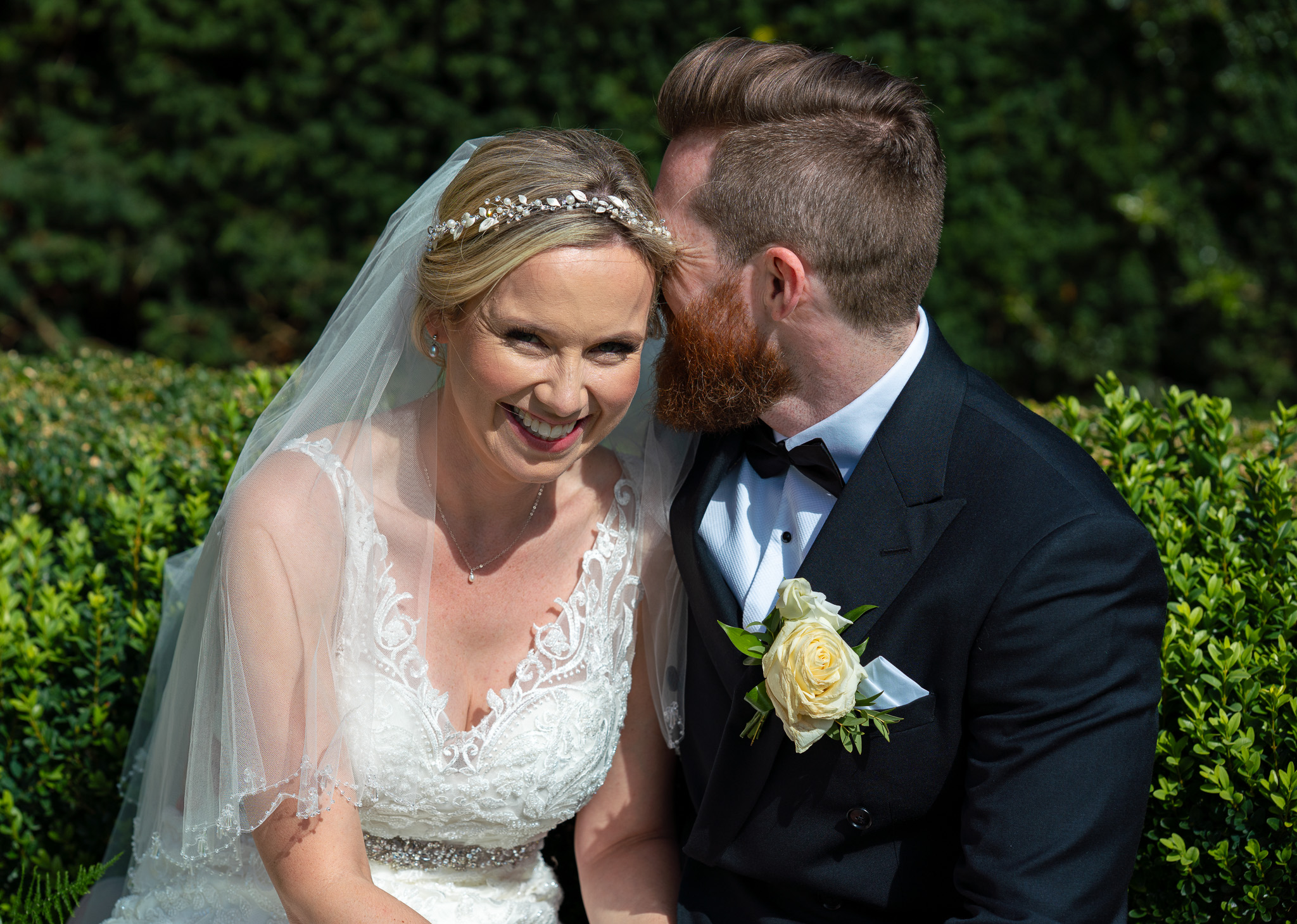 Website-1-63 Bride and groom laughing together on hay bales in a rustic barn at their Hertfordshire wedding