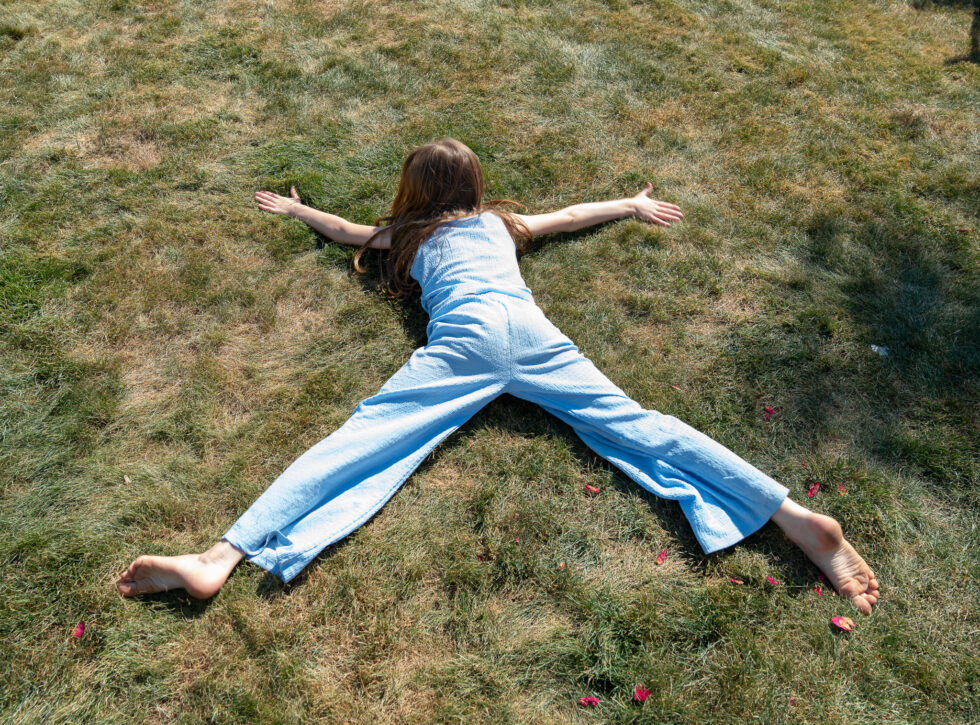 Child lying on the grass making a star shape at a wedding