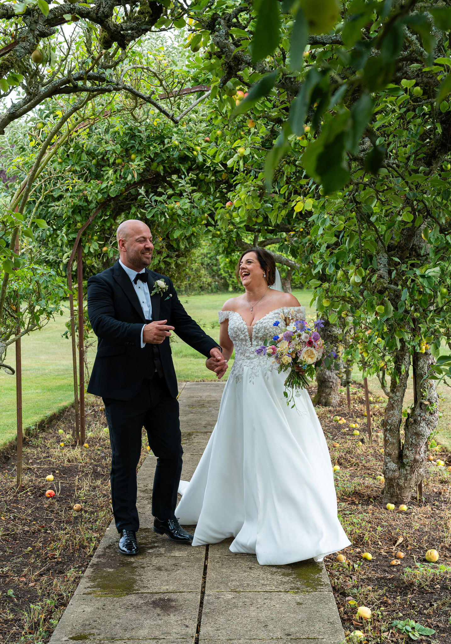 Bride and groom walking hand in hand through confetti line outside barn wedding venue in Hertfordshire