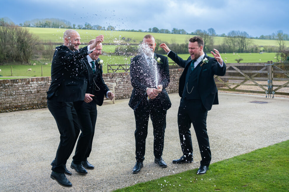 Groomsmen in suits laughing and larking about outdoors