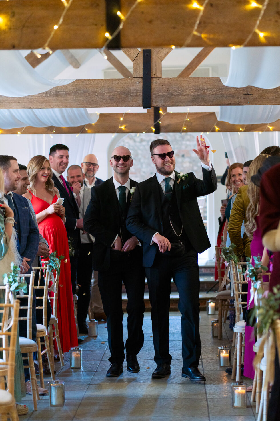 Groomsmen in sunglasses walking down a decorated aisle at a wedding