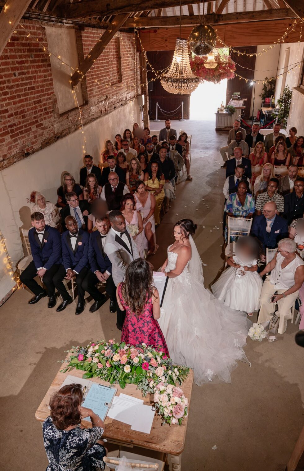 Bride walking down the aisle from above as guests look on in a barn venue