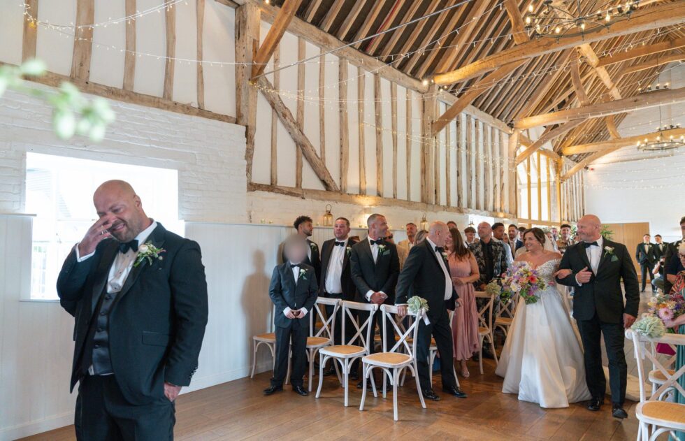 Wedding guests seated in a rustic barn waiting for the ceremony to begin